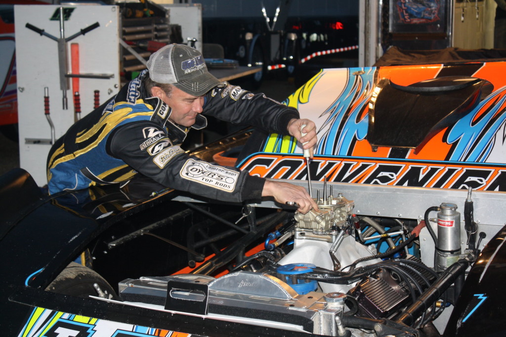 Vic Hill adjusts on the engine of Eric Wells' car